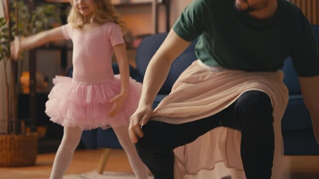 Little girl and her funny dad in skirts warming up before pretend ballet dance
