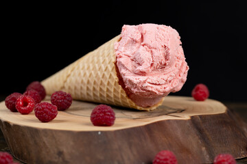 ice cream on a walnut board close up, ripe red raspberries and raspberry cold natural ice cream on the table, side view