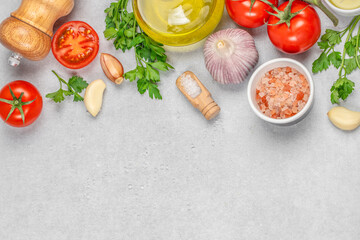 Ingredients for cooking cherry tomatoes, parsley, garlics, spices on marble table with copy space, top view