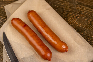 pork sausage fried in oil, meat sausages on food paper, closeup