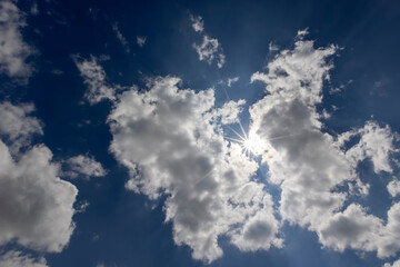 sky with clouds in sunny bright weather, natural blue sky with cumulus clouds illuminated by sunlight