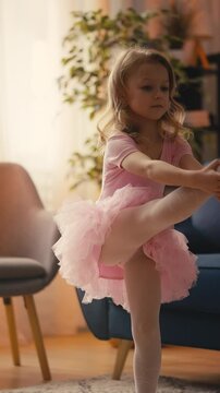 Funny five-year-old girl in tutu practicing ballet pose, fun childhood activity