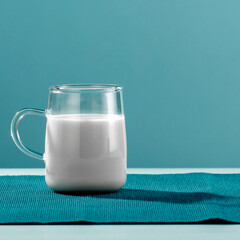 Glass of milk on white table with blue wall background. Copy space for text and product.