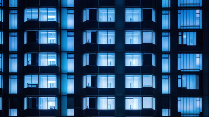 Obraz premium Symmetrical Urban Architecture with Blue Window Lights on Contemporary Building