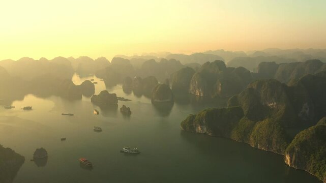 Golden sunrise over Ha Long Bay, Vietnam, with tourist boats navigating the calm waters between lush green islands