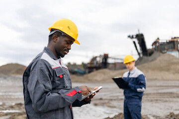 Portrait African man adult surveying engineer use tablet computer for control in sand quarry ore...
