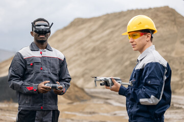 Uav drone technology in sand quarry industry, african male engineer and caucasian male surveyor...