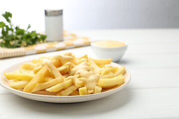 French fries with cheese sauce on white wooden table, closeup. Space for text
