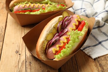 Tasty hot dogs with vegetables on wooden table, closeup