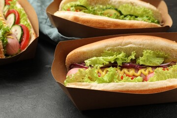 Tasty hot dogs with vegetables on black table, closeup
