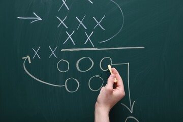 Man drawing American football game scheme on chalkboard, closeup