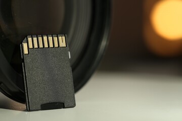 SD memory card and photo camera on white table, closeup. Space for text