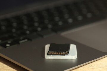SD memory card, holder and laptop on wooden table, closeup