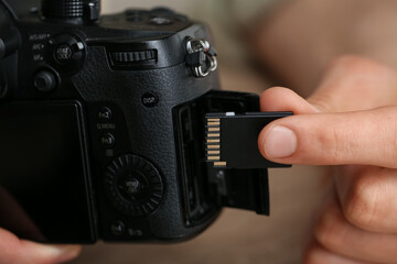 Man inserting SD memory card into photo camera, closeup