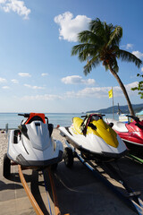 Obraz premium Jet Skis on Tropical Beach with Palm Trees Under Clear Blue Sky and Sunlight Reflections