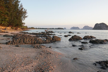 Serene Beach Landscape with Rocky Shoreline and Calm Waters at Sunrise Amidst Lush Nature