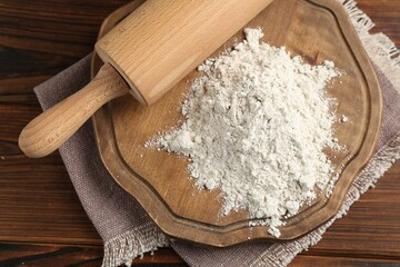 Pile of flour and rolling pin on wooden table, top view