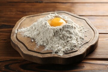 Pile of flour and egg on wooden table, closeup