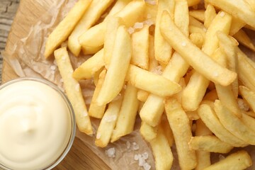 Tasty french fries served with mayonnaise on wooden table, top view