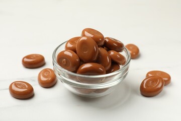 Many tasty caramel candies on white table, closeup