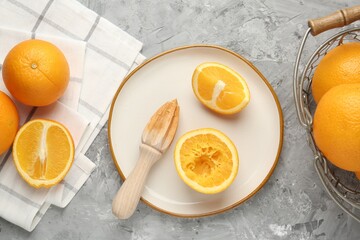Wooden juicer and fresh oranges on grey table, flat lay