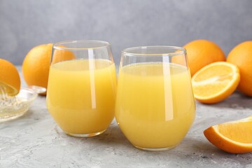 Orange juice in glasses and fresh fruits on grey table, closeup