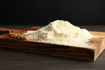 Pile of flour and spike on dark wooden table against black background, closeup