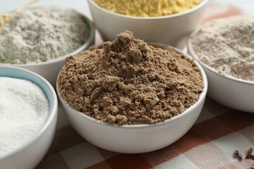 Different types of flour in bowls on table, closeup