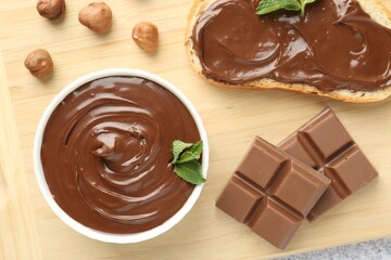 Tasty chocolate spread, toast, hazelnuts and mint on table, top view