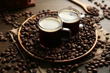 Aromatic coffee in cups and beans on wooden table, closeup