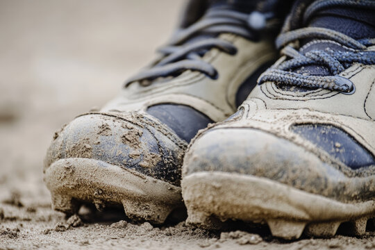 Mud-Covered Baseball Cleats Closeup. Muddy baseball cleats in close-up, showing the texture of the dirt and the wear on the shoes, ideal for sports-related visuals.