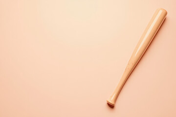 Obraz premium Baseball Bat on Peach Background. A wooden baseball bat lays diagonally against a peach-colored background, a simple but effective sports themed image.