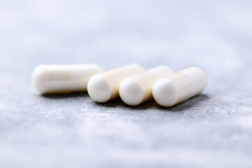 Creatine capsules on bright wooden background. Soft focus. Close up. Copy space.	