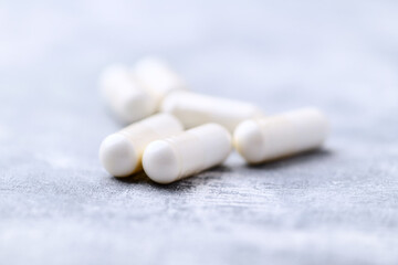 Creatine capsules on bright wooden background. Soft focus. Close up. Copy space.	