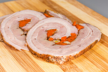 Baked pork belly roll slices on cutting board, close-up