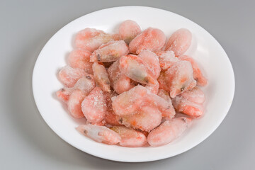 Shrimps in ice glazing on dish on gray background