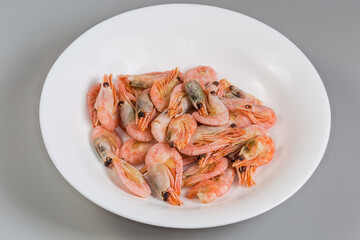 Whole boiled shrimps on dish on a gray background
