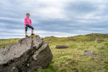 Obraz premium A Young Explorer is Standing Boldly on a Large Rock in a Beautiful Icelandic Landscape Beneath the Sky
