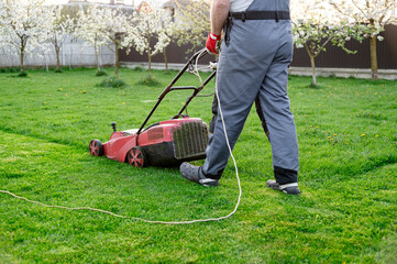 Lawn care in springtime with a homeowner mowing grass in a landscaped garden setting