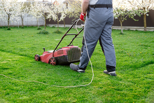 Lawn care in springtime with a homeowner mowing grass in a landscaped garden setting