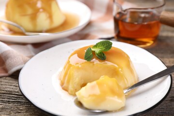 Delicious pudding with caramel sauce and mint served on wooden table, closeup