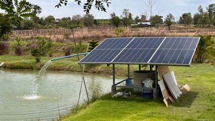 Solar powered water pump fills the pond on a sunny day with green grass and trees in the background...