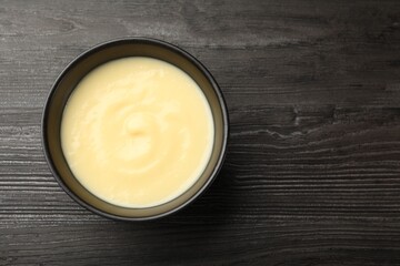 Tasty vanilla pudding in bowl on wooden table, top view. Space for text