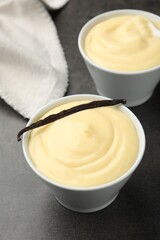 Tasty vanilla pudding with pod on black table