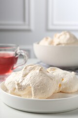 Delicious homemade meringue cookies and tea on light table, closeup