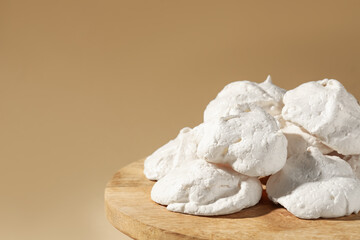 Delicious homemade meringue cookies on wooden table against beige background, closeup. Space for text