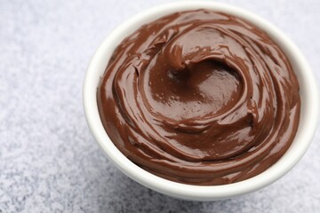 Delicious chocolate pudding in bowl on light grey textured table, closeup. Space for text