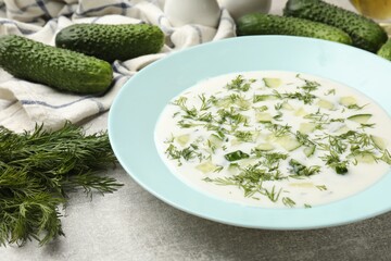 Tasty cucumber soup with dill on grey textured table, closeup