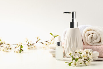 Spa products, pebble stones and twigs with beautiful flowers on white table, closeup