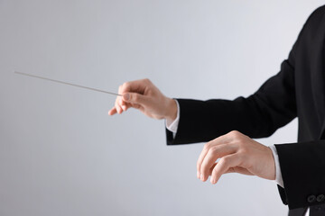 Professional conductor with baton on light grey background, closeup. Space for text